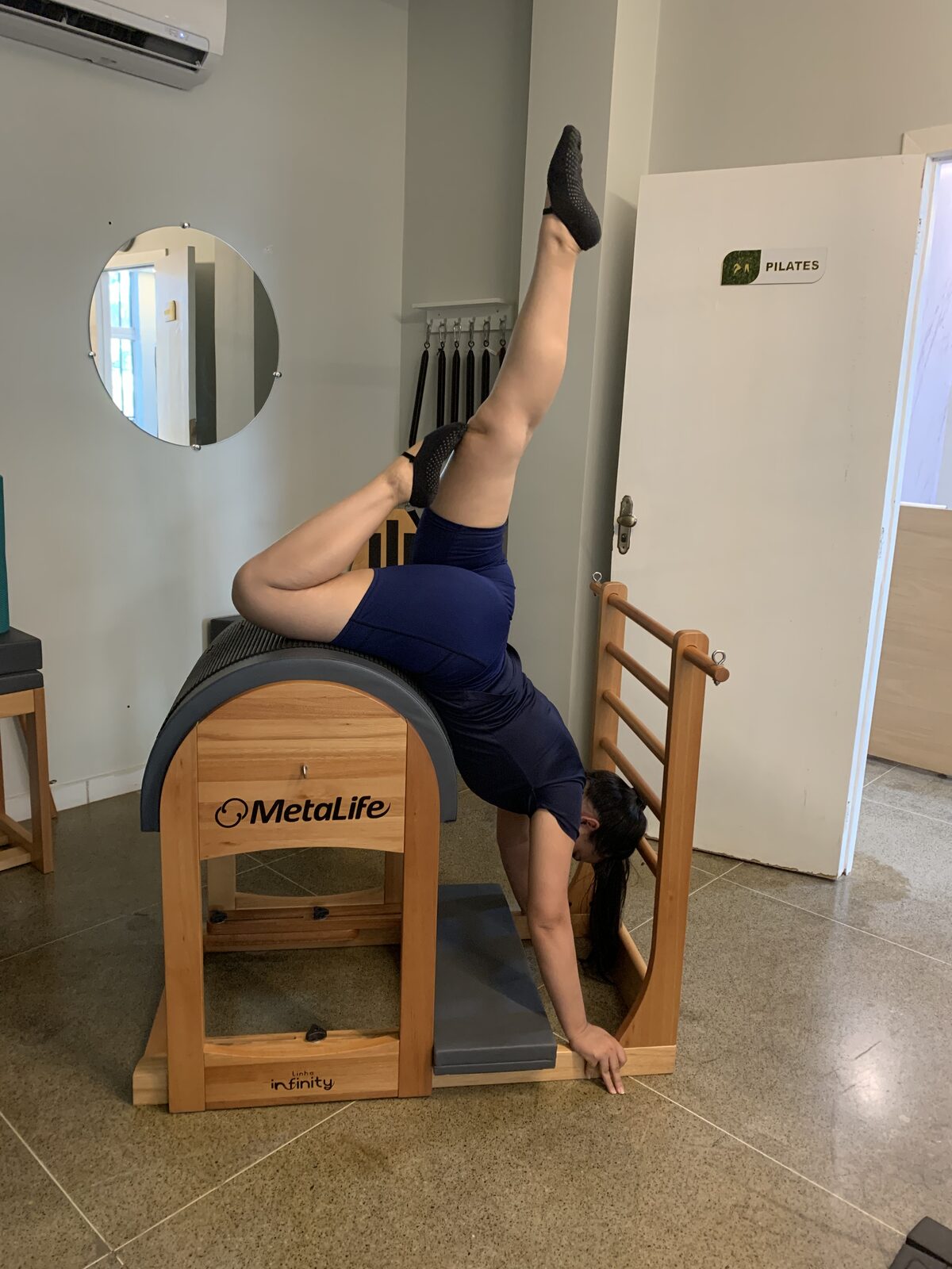 Aluna em pose invertida no barril de pilates