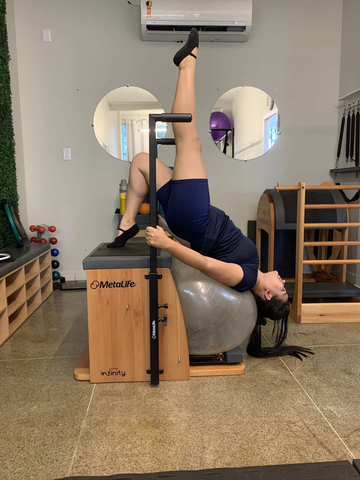 Aluna em ponte com bola suíça no estúdio de pilates
